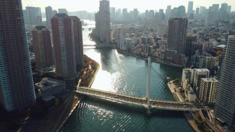 Aerial-Drone-Flying-Over-River-Between-High-Rise-Buildings-In-Tokyo-City-Japan