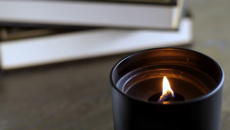 A-black-candle-on-a-coffee-table-in-front-of-a-small-pile-of-books