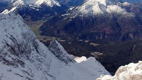 Dramatische-Luft-Den-Felsigen-Gipfel-Eines-Schneebedeckten-Berges-Hinab-In-Das-Grüne-Tal-Darunter