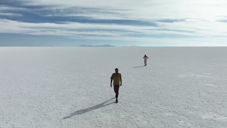 Uyuni,-Bolivien---Touristenfreunde,-Die-Allein-Mit-Freiheit-Am-Wüstenartigen-Salar-De-Uyuni-Laufen,-Der-In-Romantischer-Zeitlupe-Mit-Wasser-Und-Salz-Bedeckt-Ist