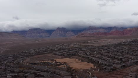 Antenne-Breite-Absteigende-Aufnahme-Von-Red-Rock-Canyon-Mit-Wüstenvororten-Im-Vordergrund-In-Las-Vegas,-Nevada