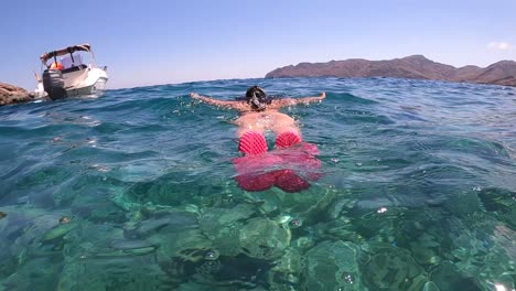 Young-girl-diving,-snorkelling-underwater,-scuba-diving-at-mediterranean-sea-looking-for-fish-during-summertime