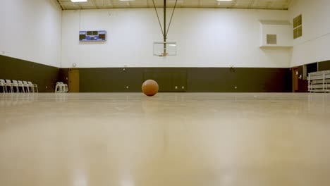 Basketball-ball-rolling-on-the-floor-of-Empty-Basketball-court,-Static-shot