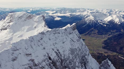 Antenne-Eines-Schneebedeckten-Gipfels-In-Den-Alpen-Mit-Dem-Grünen-Tal-Unten