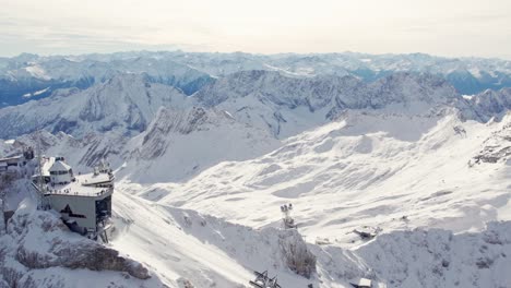 Sobrevuelo-Impresionante-Edificio-De-La-Cumbre-En-Zugspitze-En-Los-Alpes-Con-Nieve-Y-Vista-Del-Glaciar