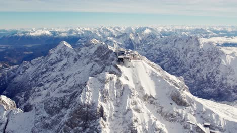 Antena-Orbitando-Alrededor-De-La-Cumbre-De-Zugspitze,-Un-Pico-De-Montaña-Nevado-En-Los-Alpes-Con-Un-Impresionante-Edificio-En-La-Parte-Superior