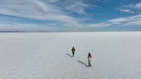 Uyuni,-Bolivien---Touristenfreunde,-Die-Allein-Mit-Freiheit-Am-Wüstenartigen-Salar-De-Uyuni-Laufen,-Der-In-Romantischer-Zeitlupe-Mit-Wasser-Und-Salz-Bedeckt-Ist