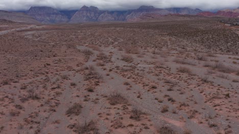 Low-aerial-shot-tilting-up-to-reveal-Red-Rock-Canyon-blanketed-by-thick-clouds-in-Las-Vegas,-Nevada