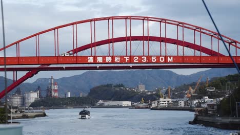 View-from-a-ferry-under-passing-a-red-traffic-bridge-in-Japanese-sea