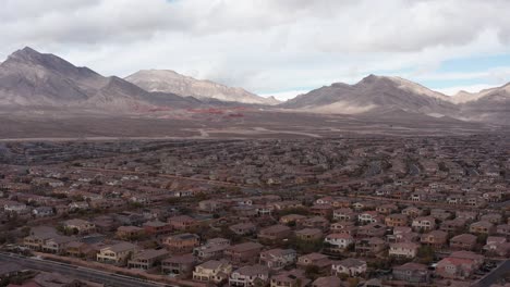 Close-up-aerial-rising-shot-of-Red-Rock-Canyon-behind-desert-suburbs-in-Las-Vegas,-Nevada
