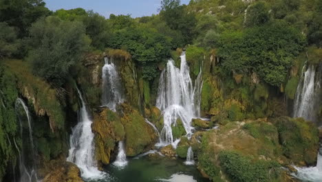 Aerial-pulls-back-from-Kravice-waterfall-in-dense-green-Bosnian-forest