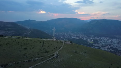 Dawn-blue-light-aerial-orbits-Millennium-Cross-on-hill-at-Mostar-Bosnia