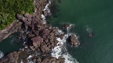 Aerial-view-over-a-rocky-bay-towards-a-beach,-in-Costa-Verde,-Brazil---tilt,-drone-shot