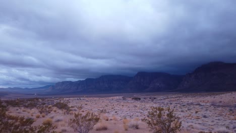 Gimbal-panning-shot-of-the-dramatic-cliffs-mired-in-thick-desert-clouds-in-Red-Rock-Canyon,-Nevada-at-low-light