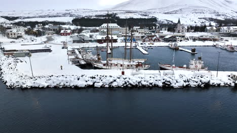 Large-sailboat-is-moored-in-the-harbor-of-Husavic-while-the-harbor-is-covered-with-white-snow