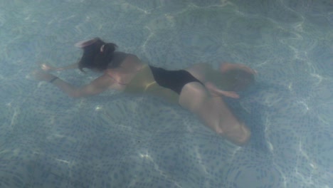 A-beautiful-young-woman-swims-underwater-inside-a-swimming-pool