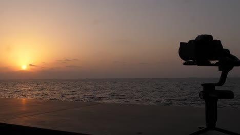 Silhouette-Of-Camera-On-Gimbal-Stabiliser-Filming-Sunset-On-Horizon-Over-Ocean-Slow-Motion-Dolly