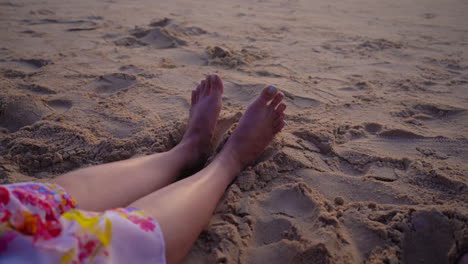 4k-video-of-legs-stretched-out-and-resting-on-the-warm,-soft-sand