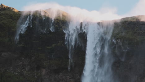 Static-view-of-reverse-waterfall-in-Iceland,-mist-blows-up-over-top-of-cliff