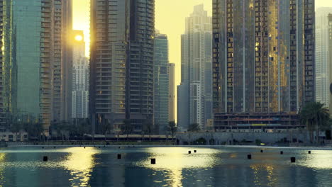 Sun-setting-between-luxurious-hotels-in-Dubai-city-while-reflecting-into-the-water-fountains