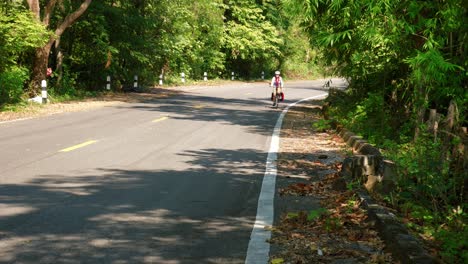 Shot-of-women-cycling-in-the-road-of-Pak-Nai-fisherman-village,-Nan-province,-Thailand