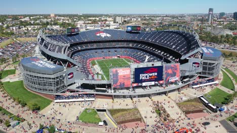 Cinematic-aerial-shot-slowly-revealing-exteriors-and-interiors-of-iconic-Empower-field-at-Mile-High-Stadium-previously-known-as-Broncos-Stadium-with-Downtown-Denver-city-view,-Colorado