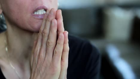 woman-praying-with-hand-over-her-face-on-grey-background-with-people-stock-video