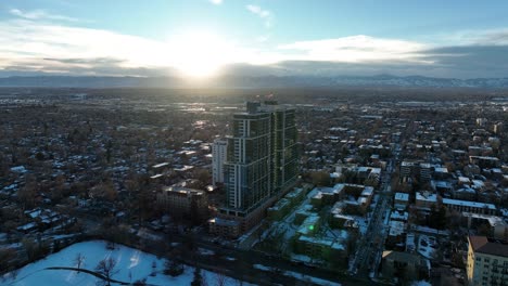 Drone-circling-around-country-club-towers-Cherry-Creek-and-slowly-revealing-city-view-of-Denver-during-sunset-and-mountain-view-at-the-backdrop,-Colorado