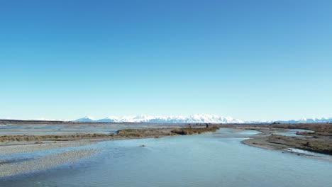 Flying-low-downstream-above-beautiful-Rakaia-River-on-a-calm,-cold-mid-winter's-morning---vast-landscape,-big-sky-and-stunning-mountains