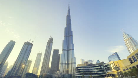 Super-wide-view-of-the-tallest-building-in-the-world,-Burj-Khalifa-with-the-sun-reflecting-on-the-glass-windows-at-sunset-near-the-Dubai-Mall