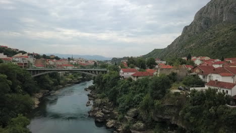 Low-aerial-flies-down-Neretva-River-to-bridge-through-Mostar-in-Bosnia