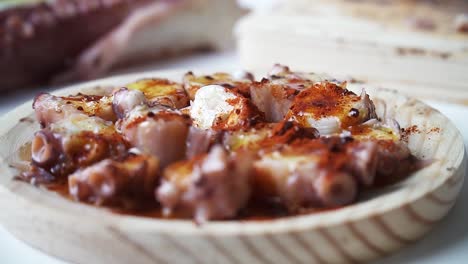 Close-up-shot-of-octopus-with-oil-and-paprika-on-a-wooden-board-being-seasoned-to-be-cooked