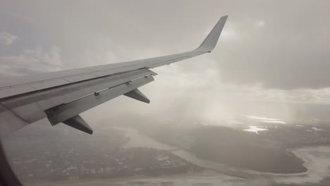 Fliegendes-Flugzeug-Durch-Wolken-Blick-Auf-Strand-Und-Stadt