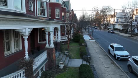 Slow-aerial-pan-from-city-street-to-front-porch,-terrace-of-historic,-victorian-home-in-America-in-winter