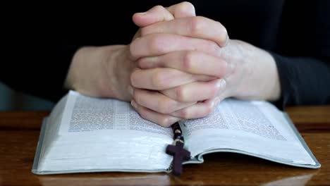 woman-praying-with-bible-on-table-with-black-background-with-people-stock-video