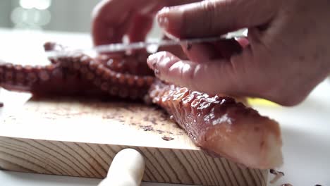 Caucasian-person-with-old-hands-cutting-octopus-tentacles-and-seasoning-them-to-be-cooked,-on-a-wooden-board