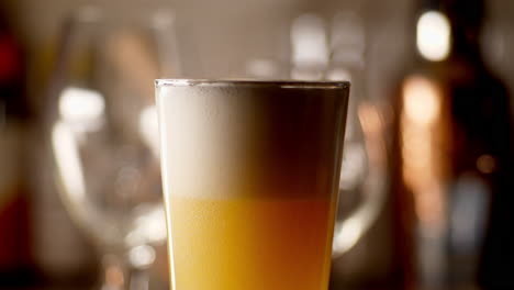 Craft-Beer-being-poured-in-to-a-pint-glass,-light-background,-close-up