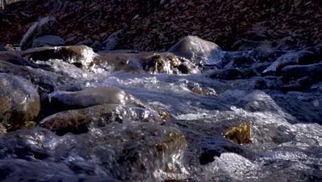 Enge-Aufnahme-Eines-Winterstroms,-Während-Wasser-über-Eisbedeckte-Steine-Fließt