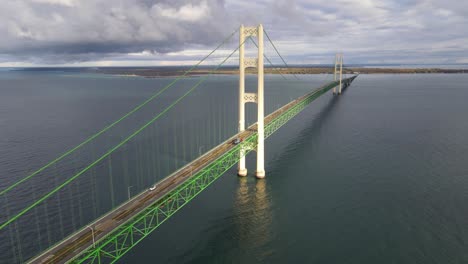 The-sun-shines-on-the-stunning-historical-Mackinaw-Bridge,-connecting-the-upper-and-lower-pennisula,-aerial-backwards-shot