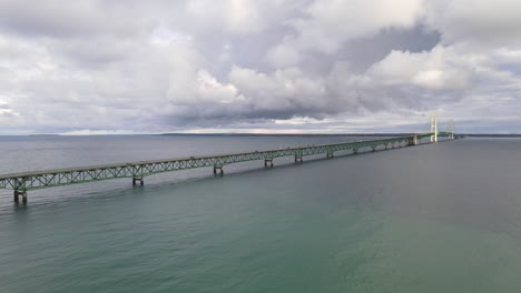 Aerial-dolly-shot-of-the-historic-Mackinac-Bridge-near-Mackinaw-city-on-a-cloudy-day-while-cars-passing-over
