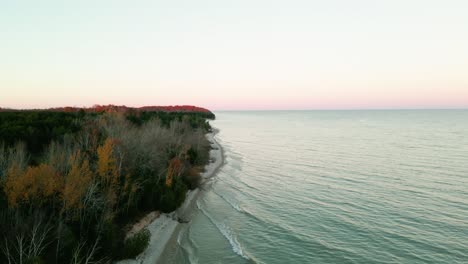 Rotating-reveal-of-panoramic-waterfront-coast-with-dense-trees-changing-colors-in-Wisconsin