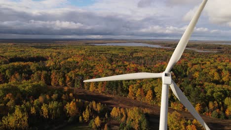 Renewable-energy-wind-turbine-in-autumn-forest,-aerial-drone-view