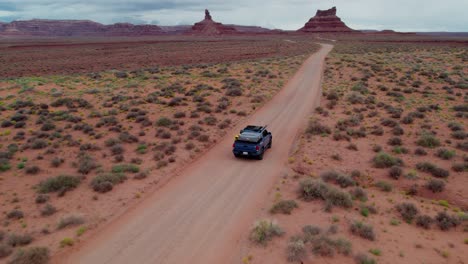 Car-driving-down-isolated-desert-road,-Valley-of-the-Gods,-Utah,-United-States