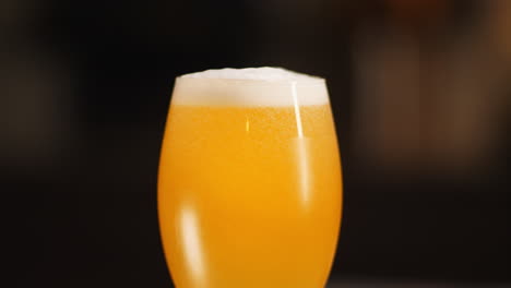 Nahaufnahme-Von-Craft-Beer,-Das-In-Ein-Meist-Volles-Kelchbierglas-Gegossen-Wird,-Dunkler-Hintergrund