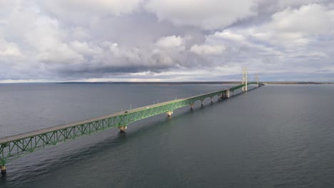 Aerial-dolly-pan-shot-of-Mackinac-Bridge-in-Michigan-USA,-cloudy-day-while-traffic-is-passing-over-the-lake