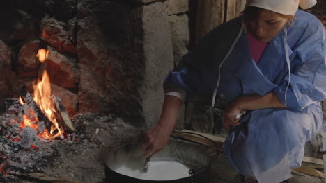 Artisan-woman-during-cheesemaking-process-in-traditional-kitchen-with-hearth