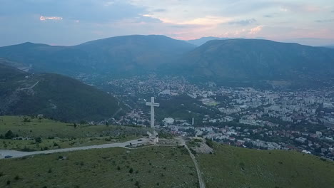 Aerial-rotates-around-enormous-cross-on-hillside-at-Mostar,-Bosnia