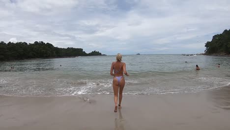 Girl-runs-to-the-water's-edge-on-the-beach-at-Manuel-Antonio-Park,-Costa-Rica