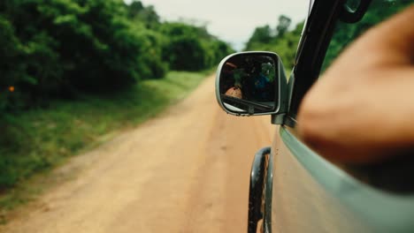 Safari-vehicle-driving-on-dirt-road-through-thick-African-bush