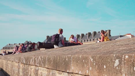 A-mother-takes-a-picture-of-her-son-sitting-on-a-canon-on-the-city-walls-of-Saint-Malo,-Brittany,-France